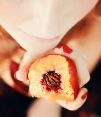 Beautiful young woman eating a peach
