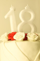 Birthday cake with red and white rose decorations and candles showing number 18