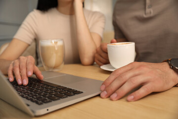 Fototapeta na wymiar Couple with coffee and laptop at cafe in morning, closeup