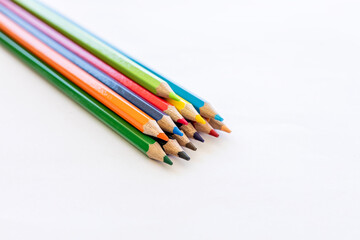 Close-up isolated, colorful pencils stacked on white paper.