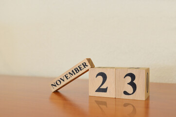 November 23, Date design with calendar cube on wooden table and white background.