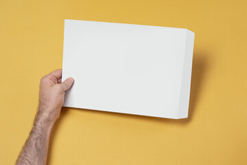 Man holding white blank A4 papers on a yellow background