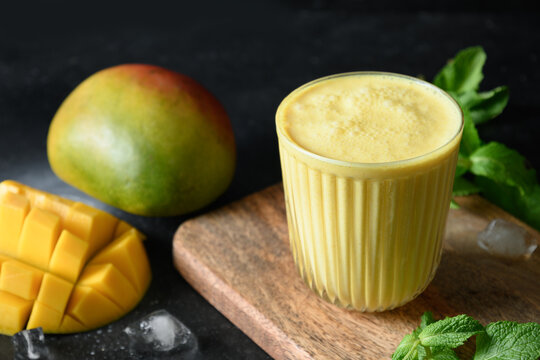Turmeric lassie or mango lassi on black background. Indian cold drink with mango. Healthy ayurvedic lassi made of yogurt, water, spices, fruits and ice cube.