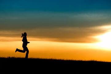 Obraz na płótnie Canvas Silhouette of girl running in sunset.