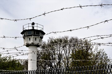 Symbole der Freiheitsberaubung - Ein Wachturm und ein Stacheldrahtzaun, 