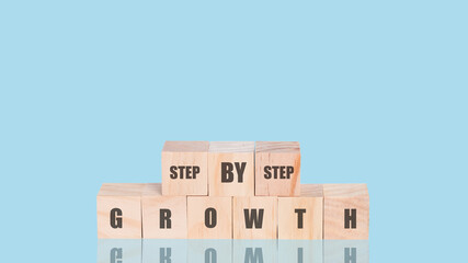 Wood cube with text of step by step and growth on blue background.