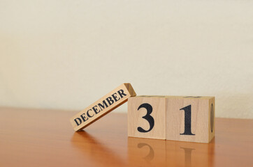 December 31, Date design with calendar cube on wooden table and white background.