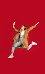 Fototapeta na wymiar Young happy girl jumping isolated over red studio background with copyspace for ad. Concept of beauty, fashion.
