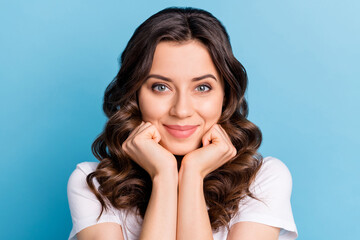 Photo of dreamy charming young woman wear white t-shirt arms cheekbones chin smiling isolated blue color background