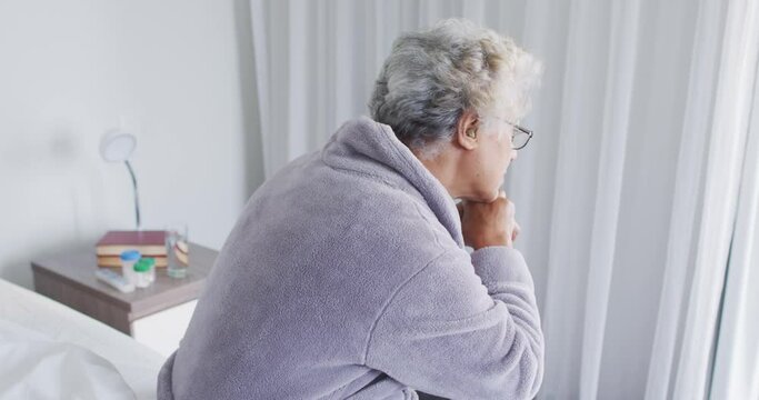 Thoughtful african american senior woman sitting on the bed at home