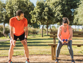 Coach guiding a woman to exercise with weights outdoors