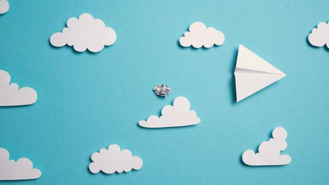 Stop Motion Animation. Papierflieger fliegt durch Wolken und blauen Himmel. Ein Zettel auf dem der Text "Endlich Urlaub" steht  entfaltet sich. 