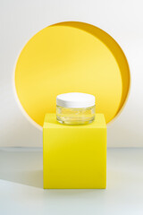 Glass cosmetic bottles with cream for skin care on special podium on yellow color background....
