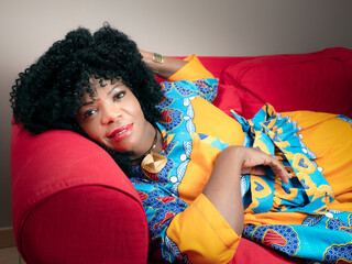 African American woman lying on a red sofa at home