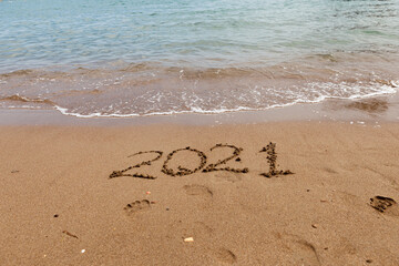 inscription on the sand 2021. Summer and rest in 2021, inscription on the beach . sea waves next to the numbers, the symbol of the year