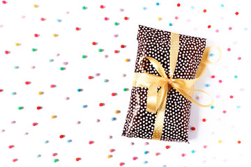 The gift is packed with wrapping paper and tied with a yellow ribbon on a white background. The concept of preparing a gift for a holiday, birthday, anniversary. Flat lay. Top view. Copy space.