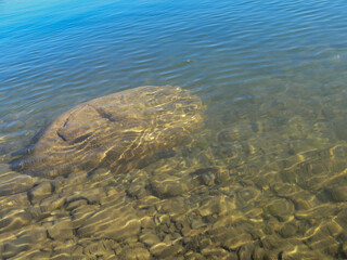 Big stone in crystal clear water with great reflections