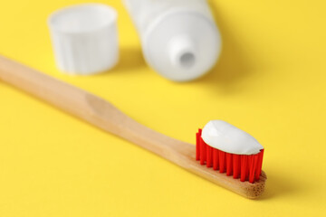 Fototapeta na wymiar Wooden brush with toothpaste on yellow background, closeup