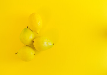 Neon yellow color trend. Minimalist depiction of summer fruit. Monochromatic fruit color. Yellow pears and lemon on an illuminate background as a symbol of the coming summer. Self - care.