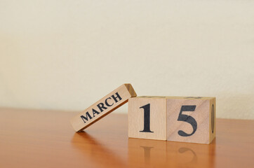 March 15, Date design with calendar cube on wooden table and white background.