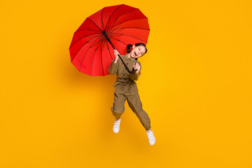 Full size portrait of energetic cheerful girl open mouth have fun hold umbrella isolated on yellow...