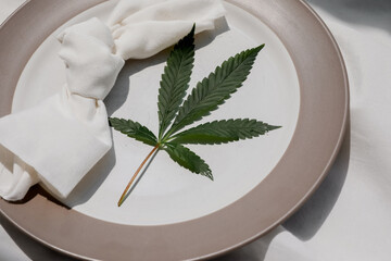 Cannabis friendly dinner concept. Beautiful dinner setup with marijuana leaves, knife and fork....
