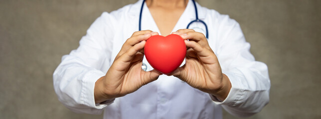 Professional doctor holding red heart shape in sideways. Health-care and medical in at hospital...