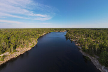Aerial panorama of a fresh water lake surrounded by rugged rocky cliffs and endless green boreal coniferous forest. Northern Ontario, Canada.