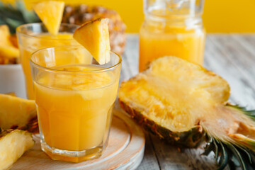 Tasty pineapple juice in glass with pineapple fruit slices. Fresh natural pineapple cocktail and juice in glass on white wooden table.