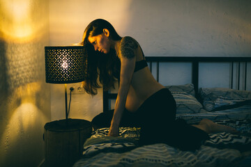 pregnant woman on the bed in the bedroom next to the bedside lamps