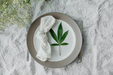 Cannabis friendly dinner concept. Beautiful dinner setup with marijuana leaves and flowers.