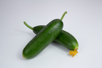 One of them with yellow flower two cucumbers on white background.