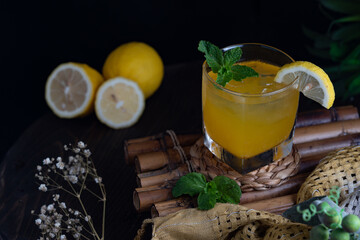 A glass of orange juice and decorated with three pieces of orange, mint leaves, cloth, other accessories.