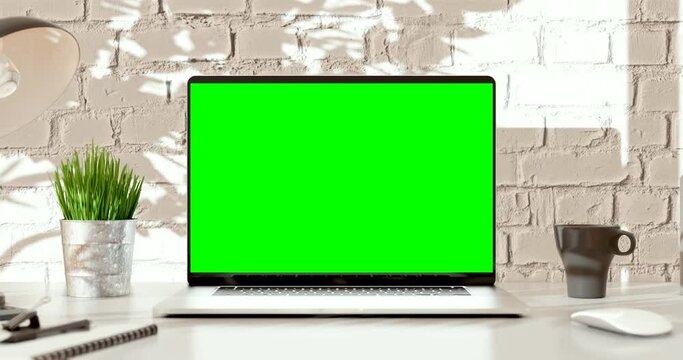 Laptop green screen. Loft office interior with brick wall and swaying trees on the wind. Loop video