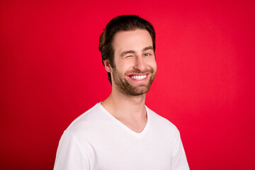 Photo of cheerful positive happy charming man wink eye good mood smile isolated on red color background