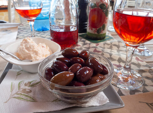 Greek snacks: Greek pickled olives, spicy cheese and rose wine in glasses on the table in a restaurant   in Delphi in Greece