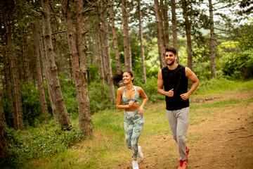 Young fitness couple running at the forest trail