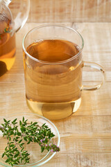 Glass cup of thyme tea and fresh thyme