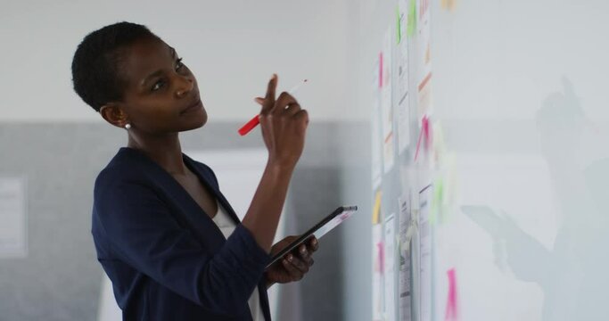 African american businesswoman thinking and making notes on whiteboard