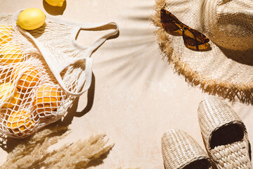 Summer flat lay on beige background. Straw hat, sunglasses, slippers and lemons in eco friendly...