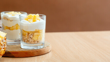 Tasty pineapple desserts with chopped fresh juicy pineapple. Breakfast dessert oat granola, greek...