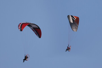 Motorized hang gliders in evening light over countryside  in spring