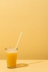 Refreshing glass of fruit juice on a yellow background in a summer day. vertical image with copy space.