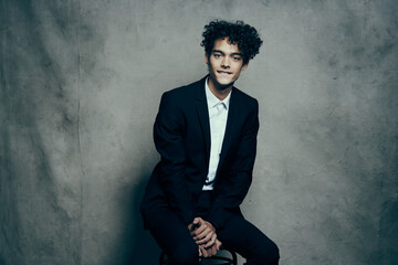 business man in a suit curly hair sitting on a chair fashion modern style