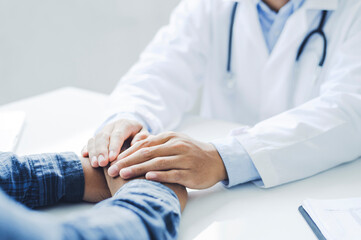 Friendly male doctor hands holding patient hand sitting at the desk for encouragement, empathy,...