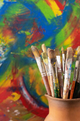 Obraz premium Paint brush in clay jug and oil painting background texture. Paintbrush painting and art still life