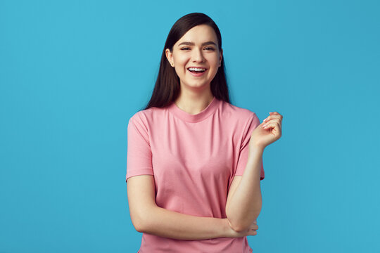 Young Lady In Pink Tshirt Smiling And Standing With Hands Crossed On Yellow