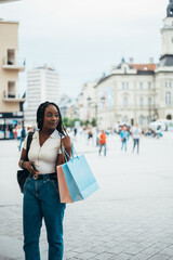Cheerful african american woman holding shopping bags and a smartphone
