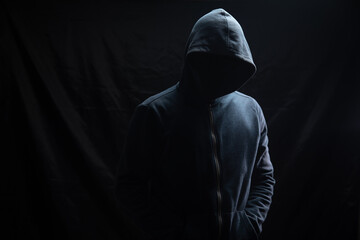 Naklejka na ściany i meble a man in a hood stands on a black background