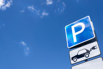 Electric car parking and recharging road sign on a blue sky background. Clean air and ecology